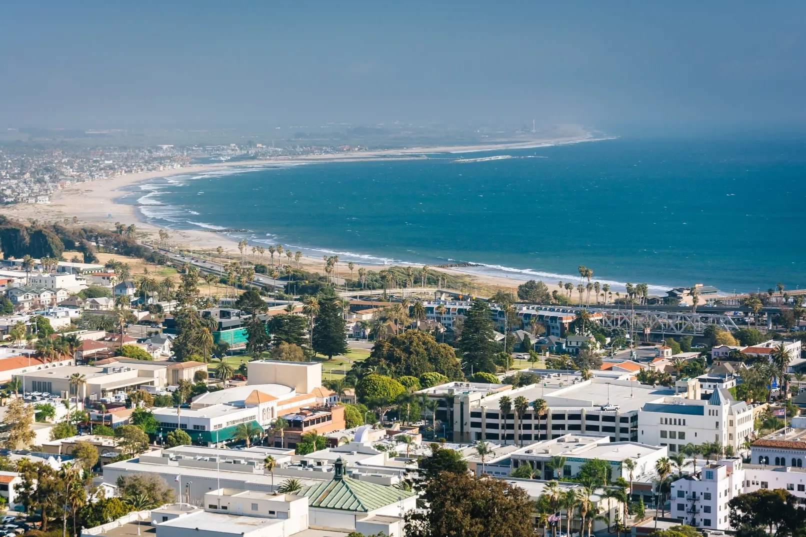 Aerial view of Ventura Coast, Southern California, showing luxury homes, buildings, sandy beach, and the blue ocean.