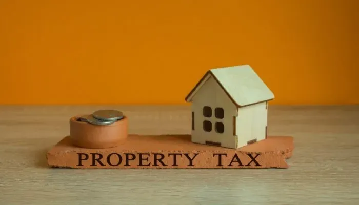 Graphic showing a model home and silver coins on a “PROPERTY TAX” base, representing real estate in Southern California.