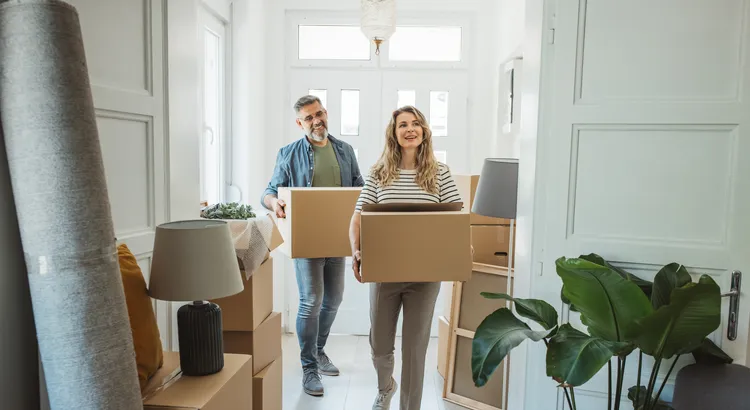 A couple holding moving boxes outside their new home in Southern California.